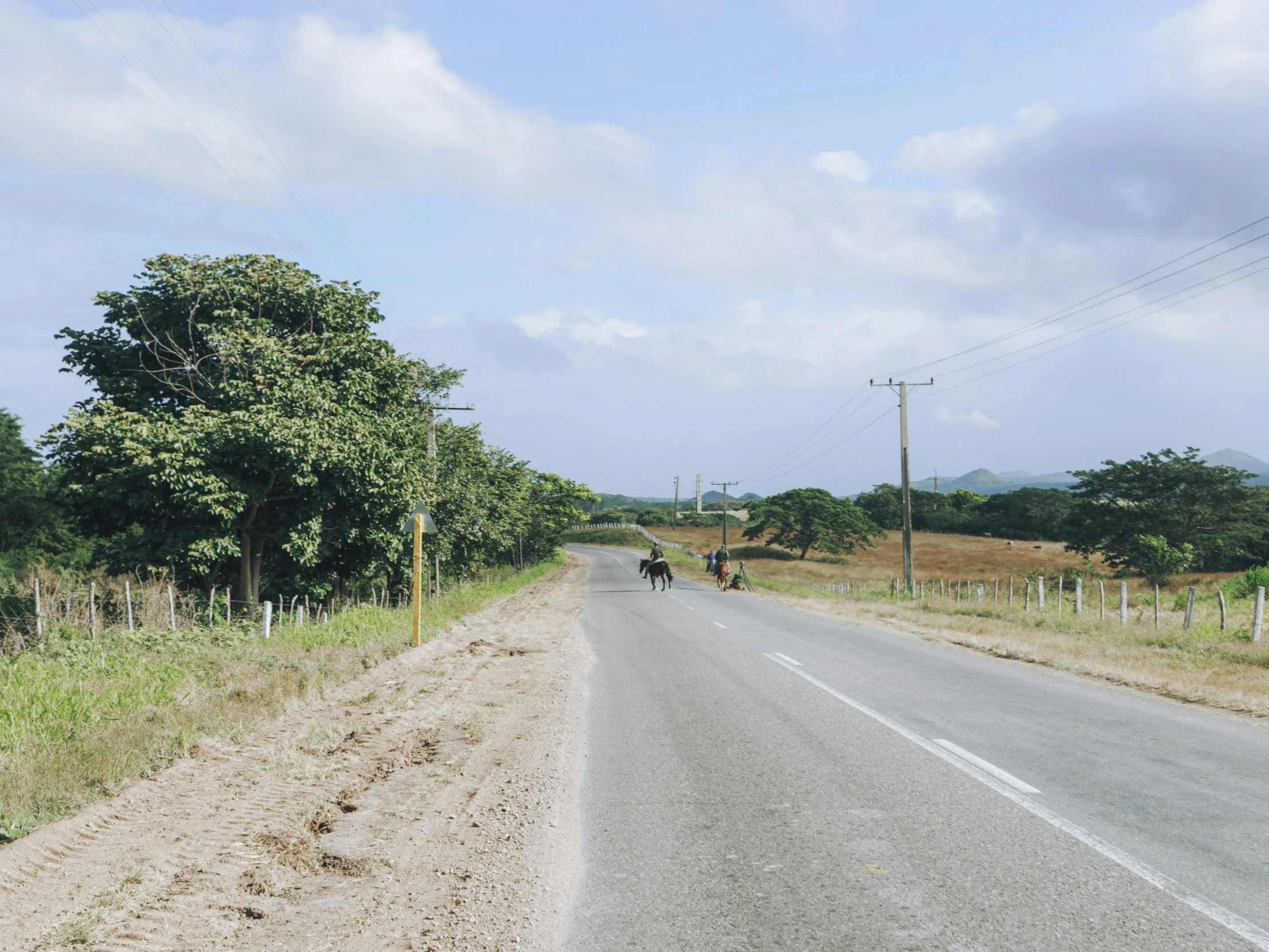 a motorcycle rider riding down a dirt road in the country