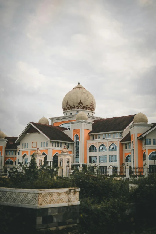 a large orange building sitting next to a lush green park