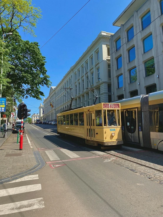 a yellow trolley is on a city street near tall buildings