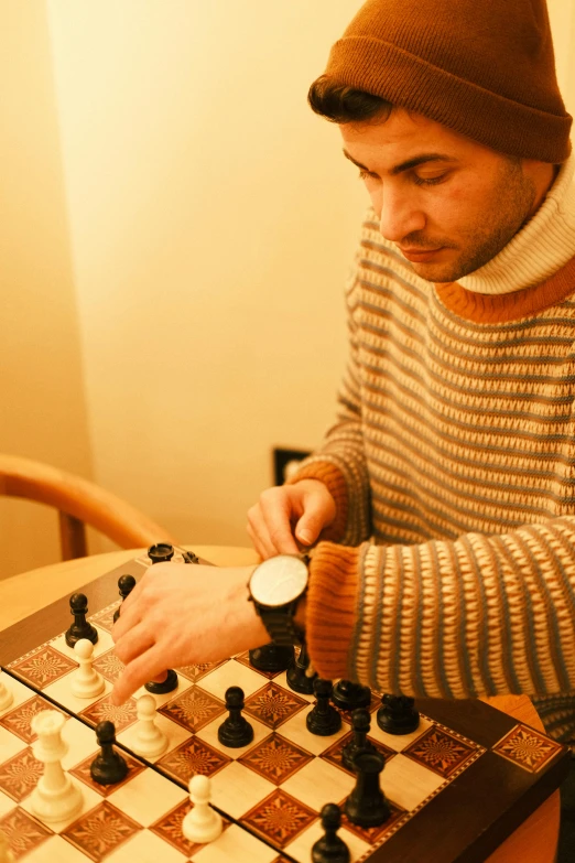 a man sits at a table with his hand on a chess board