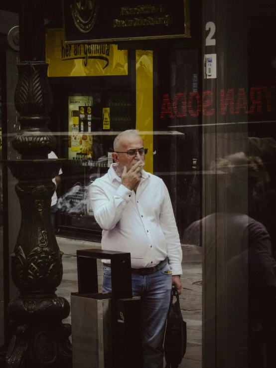 an old man with glasses, in the street talking on a cell phone