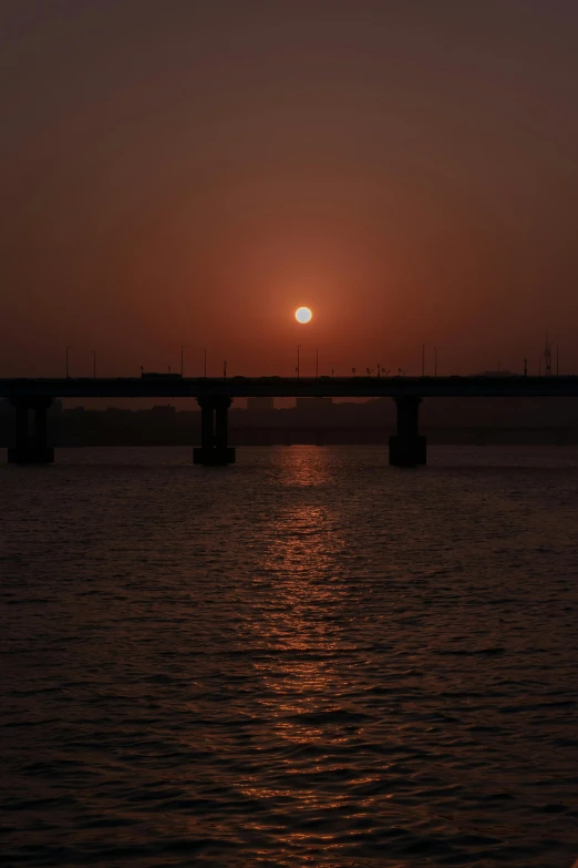 a boat sailing on a river with the sun setting in the distance