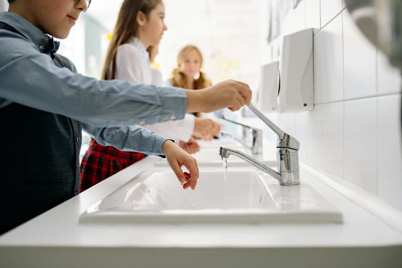 there are children standing around the sink that is clean