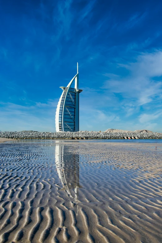 the burjhan building in the middle of the desert is reflected in the wet sand