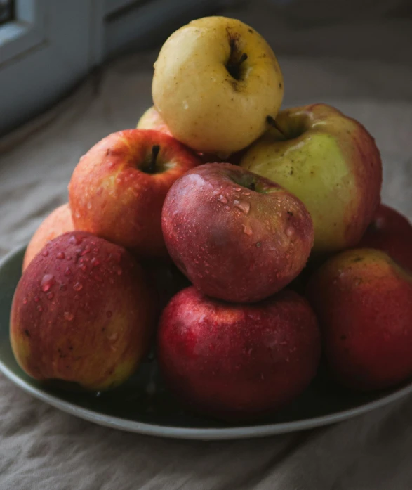 a close up of a plate of fruit with apples on it
