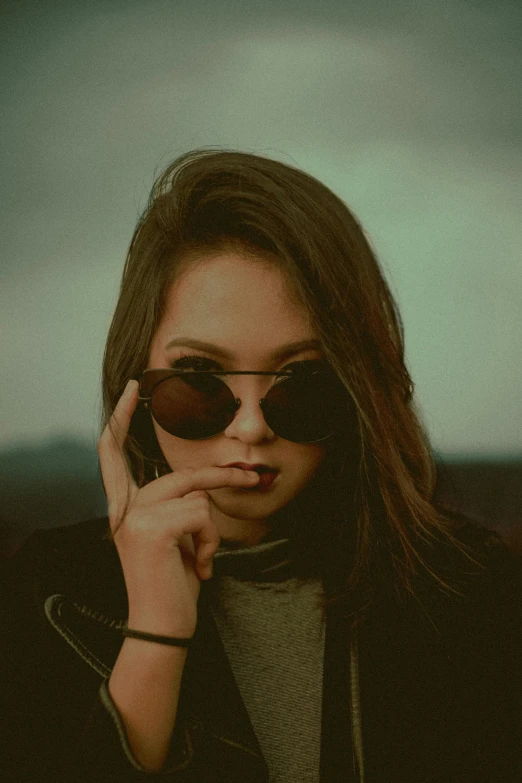 a woman wearing sun glasses holds her hand to her face