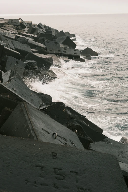 a person stands on top of the rocks near the ocean