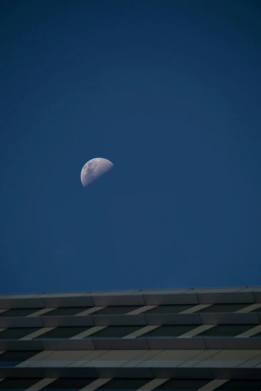 the moon is visible over a building in the sky