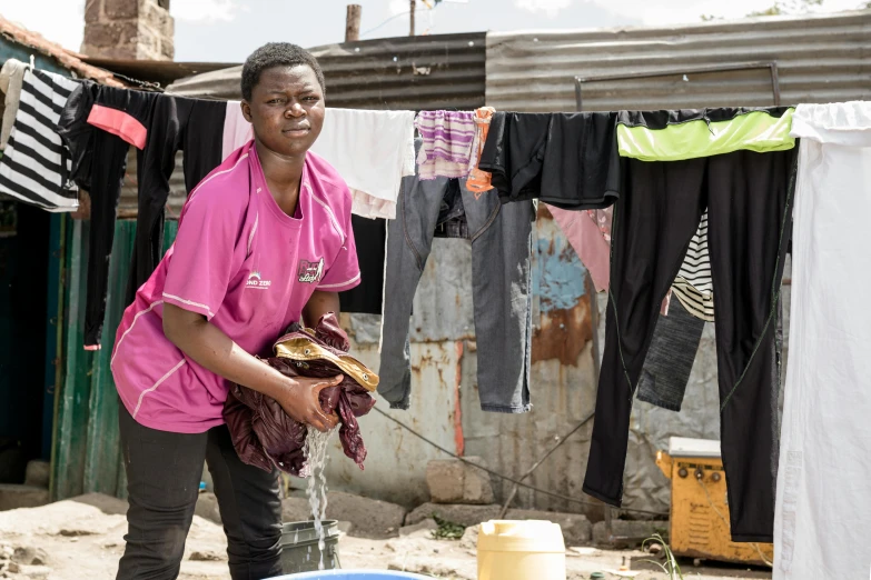 a woman is cleaning a laundry line in the dirt