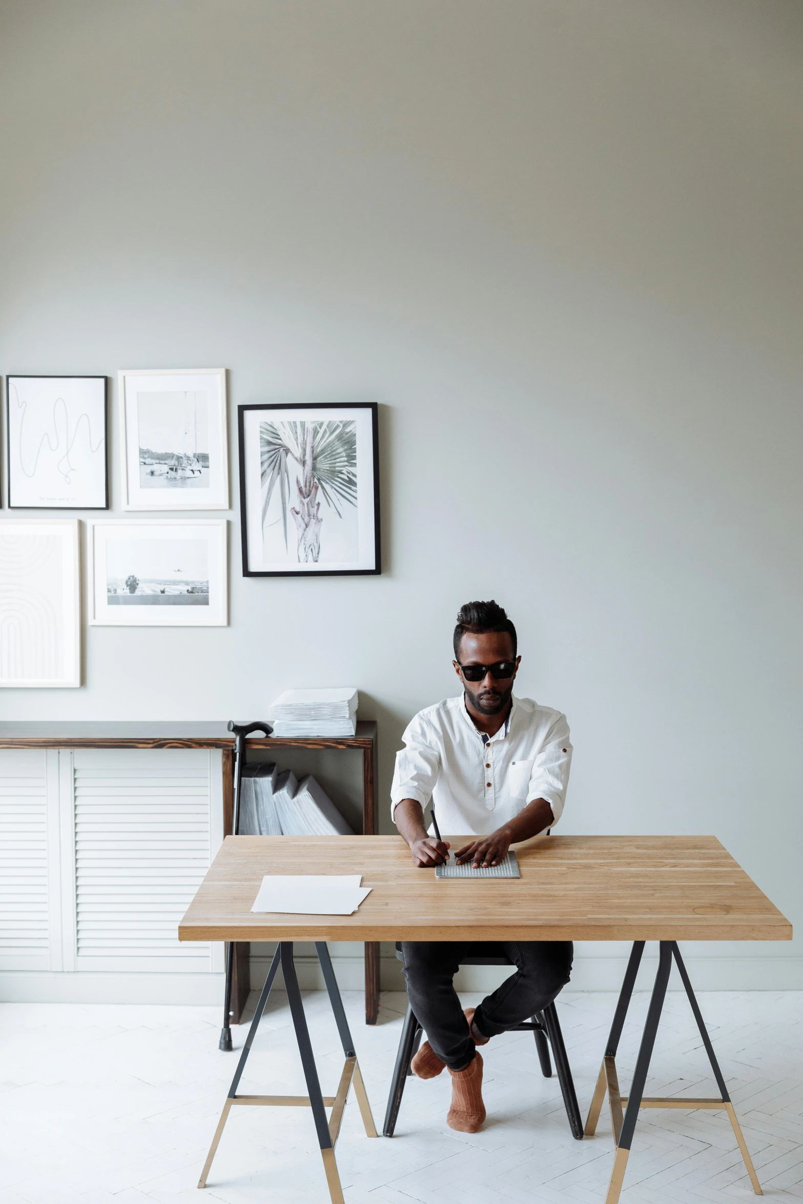 a man in white shirt and jeans seated at a desk