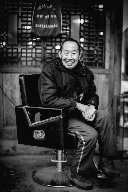 an old man in a black chair laughing