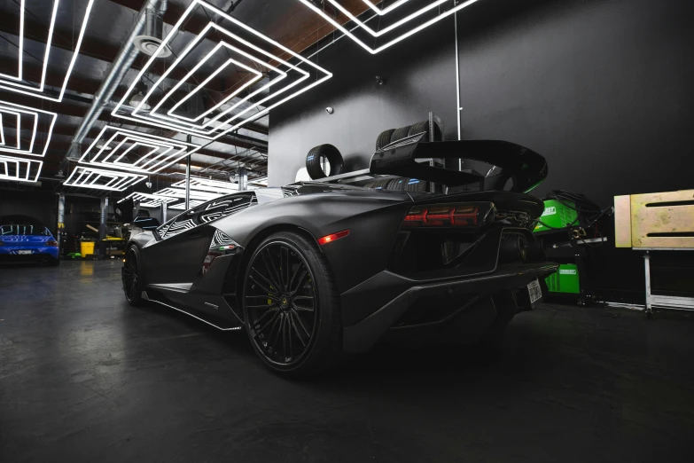 the rear end of a black sports car parked inside a garage