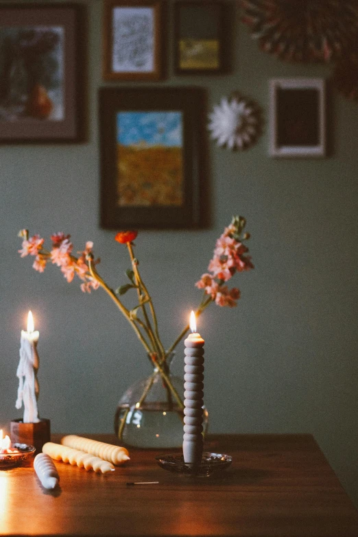 candles in a vase sit next to candles and flowers