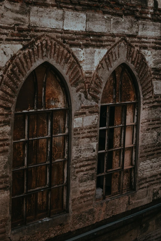 two windows on a old building with bricks