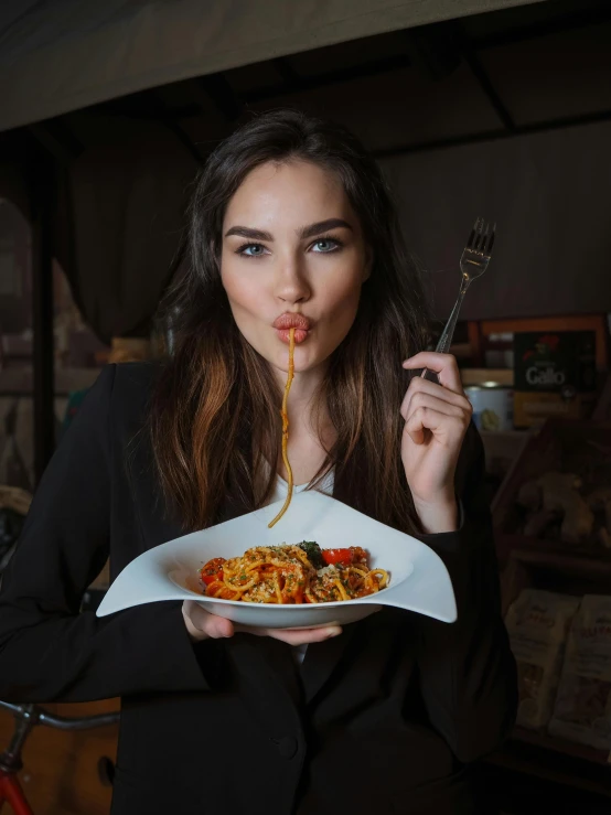 woman holding a plate of food with fork and knife in hand