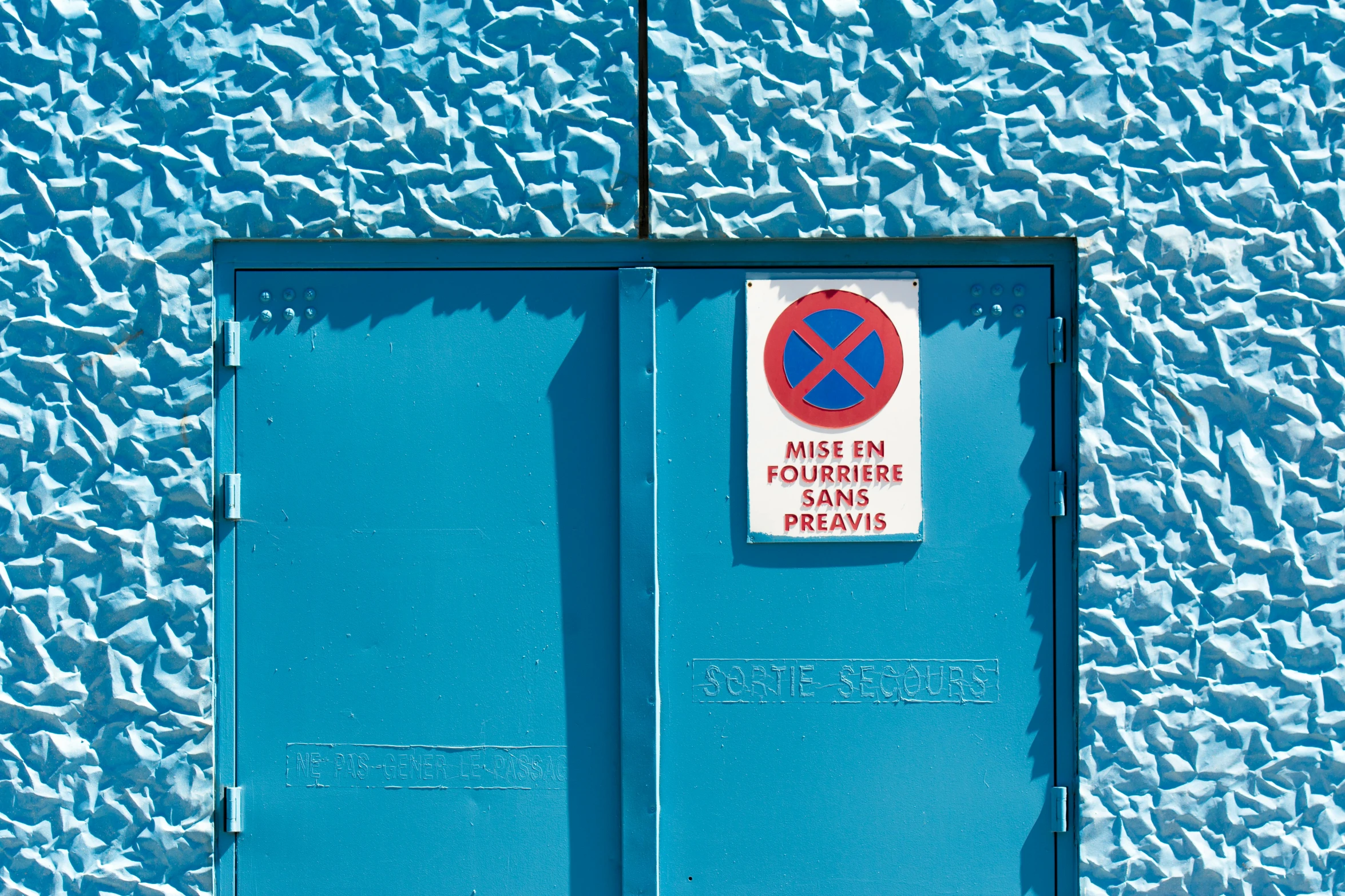 a blue door with a sign for the road crossing on it