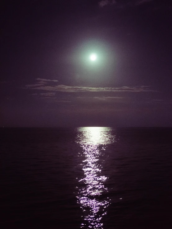 a full moon over a body of water