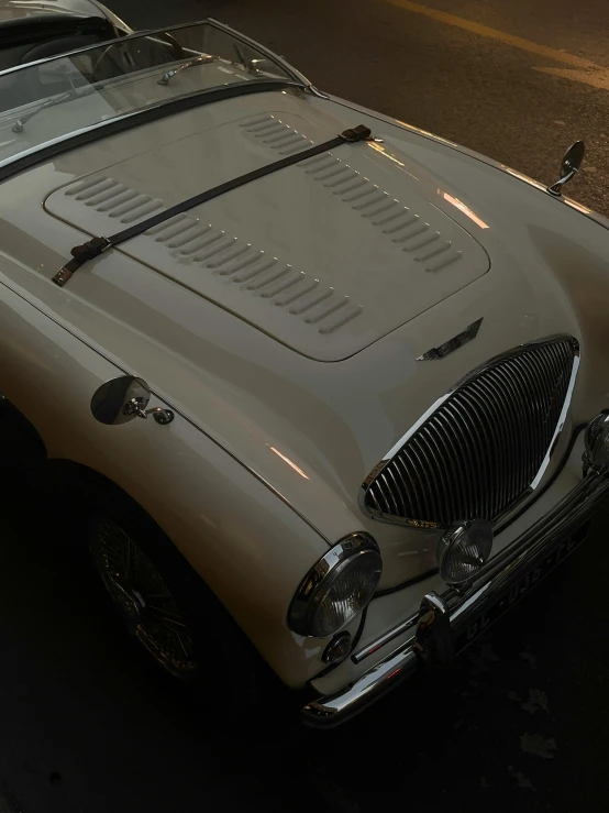 a vintage car with the hood removed on a city street