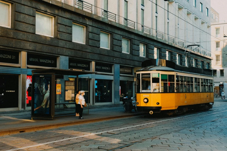 yellow and white tram on a city street with people walking around