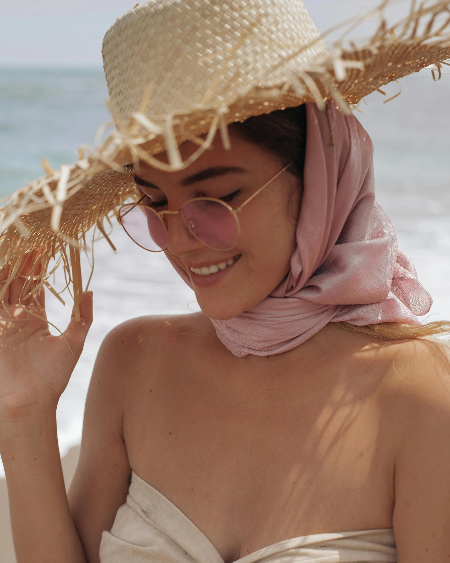 a woman in a pink scarf holding a straw hat