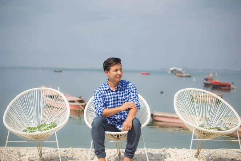 two people are sitting on a chair at the water