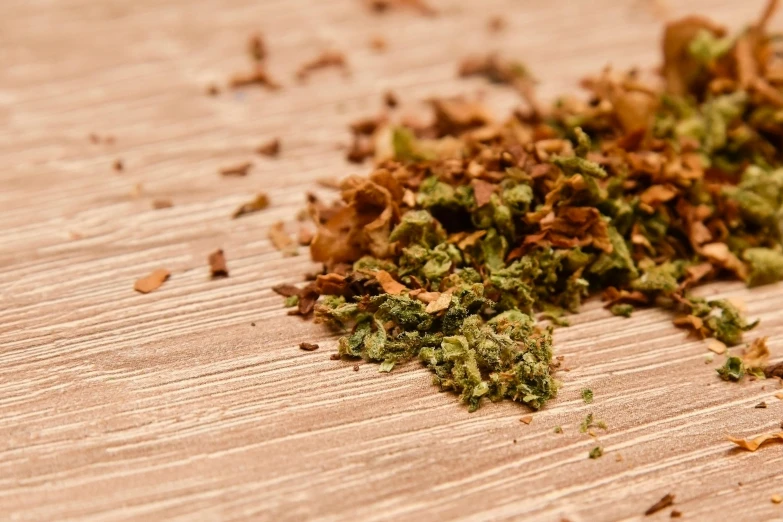 there is a pile of green herbs on the wooden table