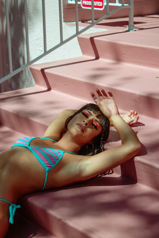 a young woman laying on some steps in a bikini