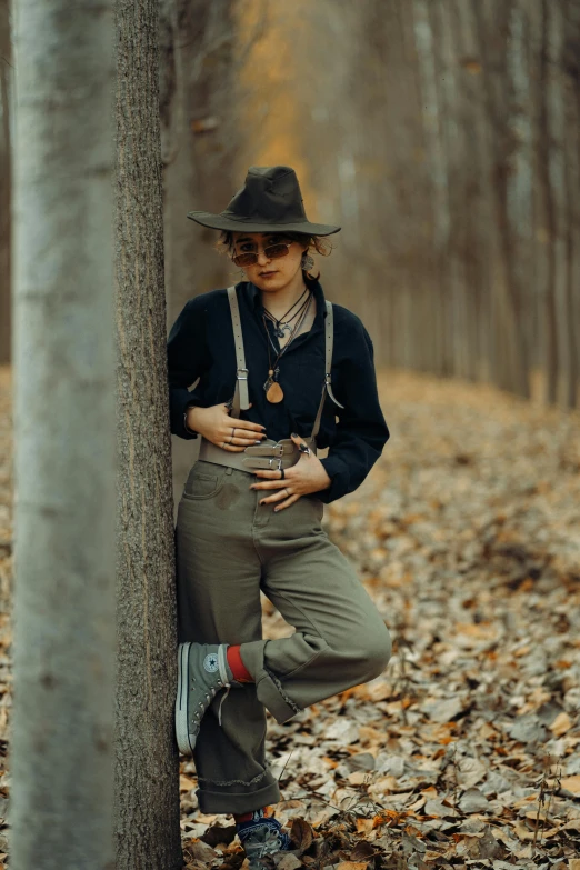 the person is leaning up against the tree and wearing overalls