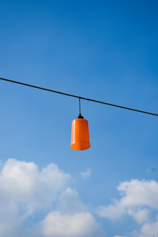 an orange colored bell hangs on a rope