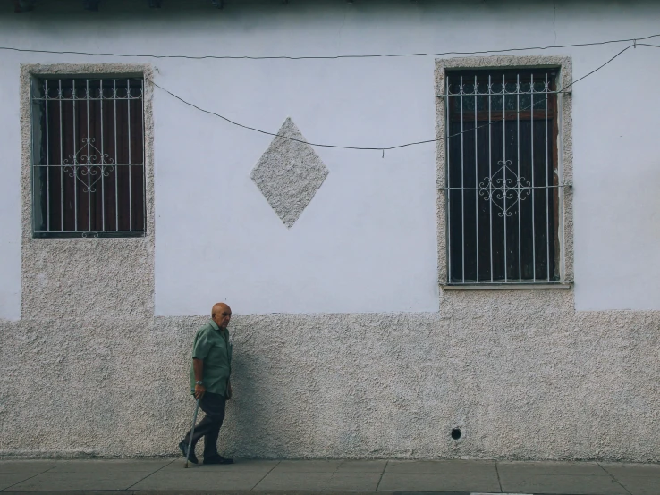 a man standing next to a wall with two windows