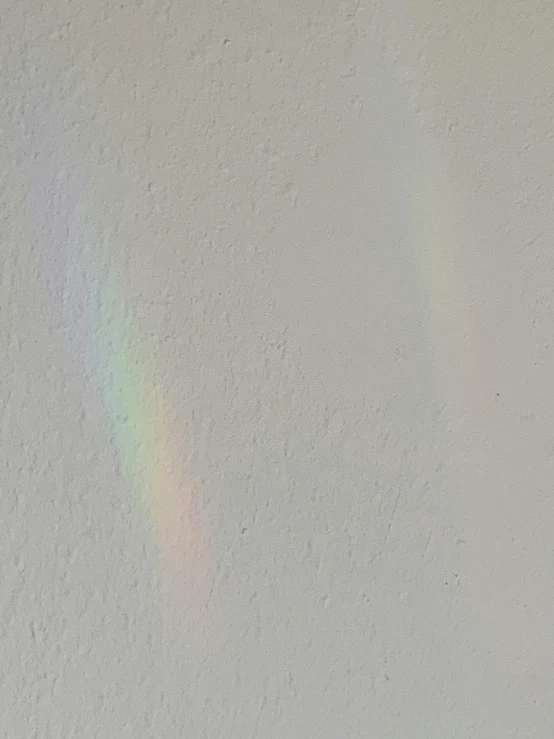 a rainbow is seen over a wall that appears white