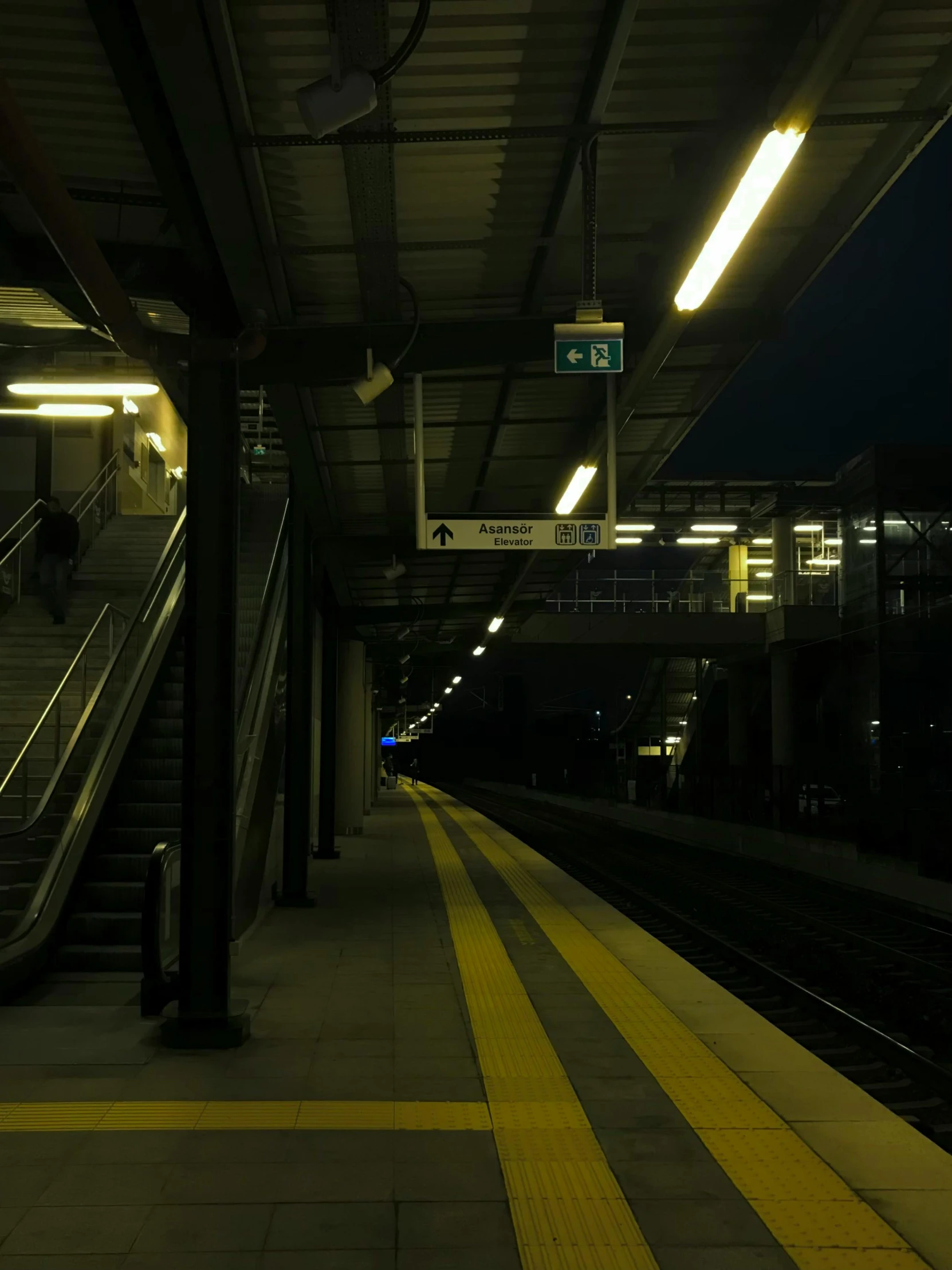 an empty train station platform with the sun going down