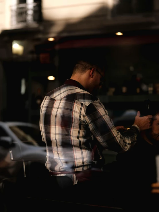 a man standing near parked cars and looking at his cell phone