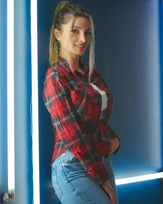 a young woman posing against a blue wall