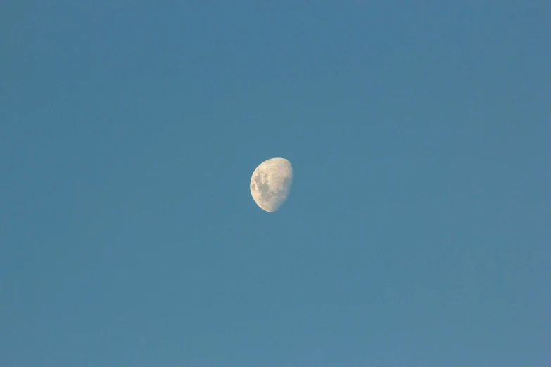 the moon rises over a clear sky with a cloud