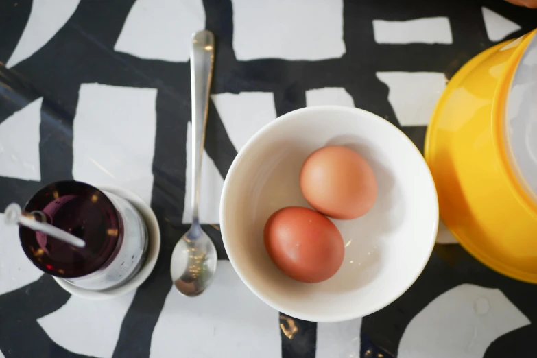 three eggs sitting in white bowls with spoons and wine