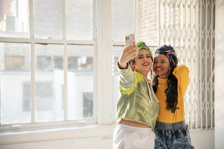 two girls are taking pictures with their cell phones