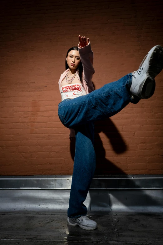 a woman standing on one leg and leaning against a wall