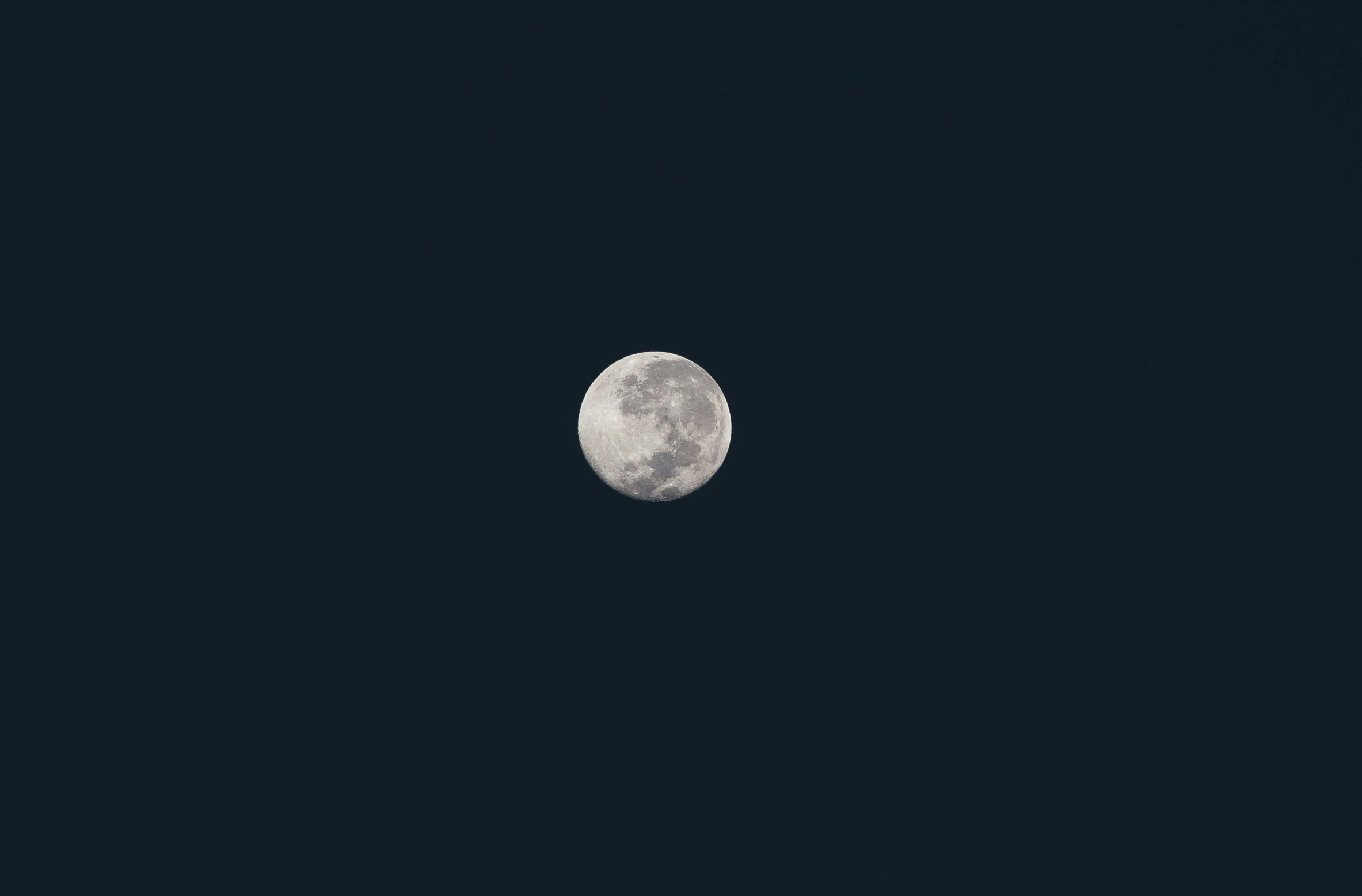 a moon is seen above the dark black night sky