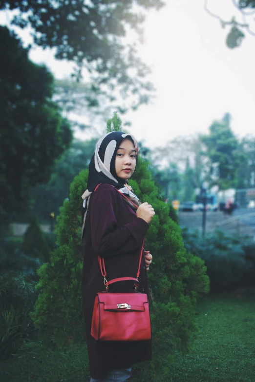 woman in maroon wearing hood with red hand bag