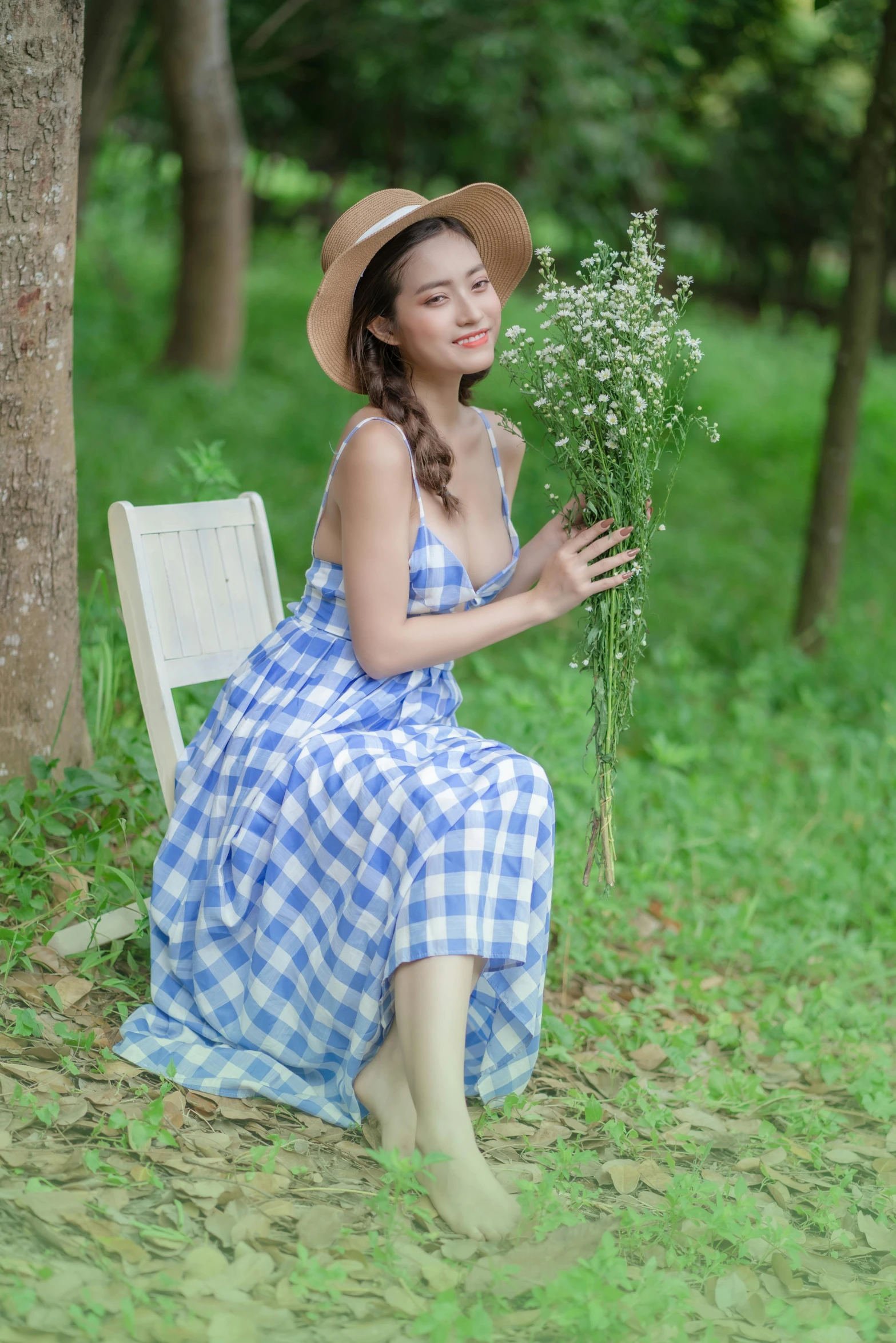 a young woman is sitting under a tree holding a bunch of flowers