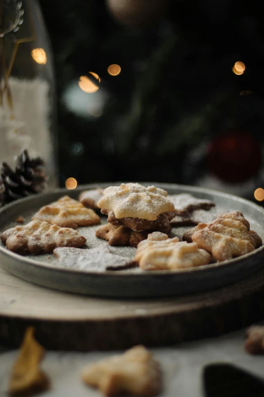 a plate full of cookies and nuts next to christmas tree