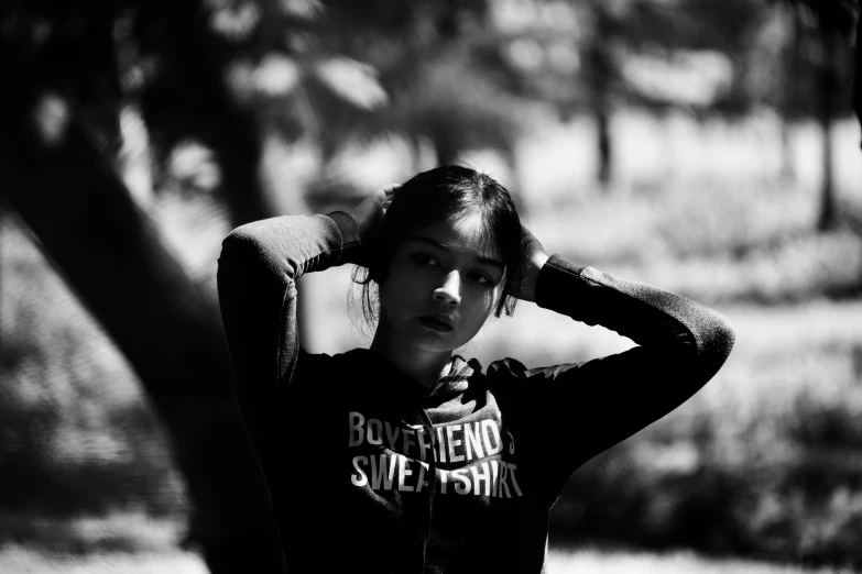 a girl with long hair and a black shirt is posing by the tree