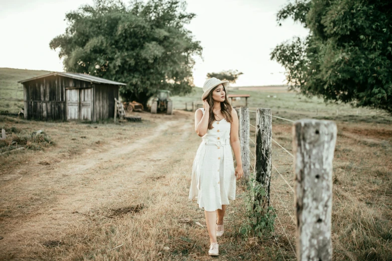 a woman standing by a fence in the middle of a field