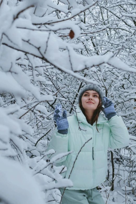 woman with mittens on her left arm in snowy forest