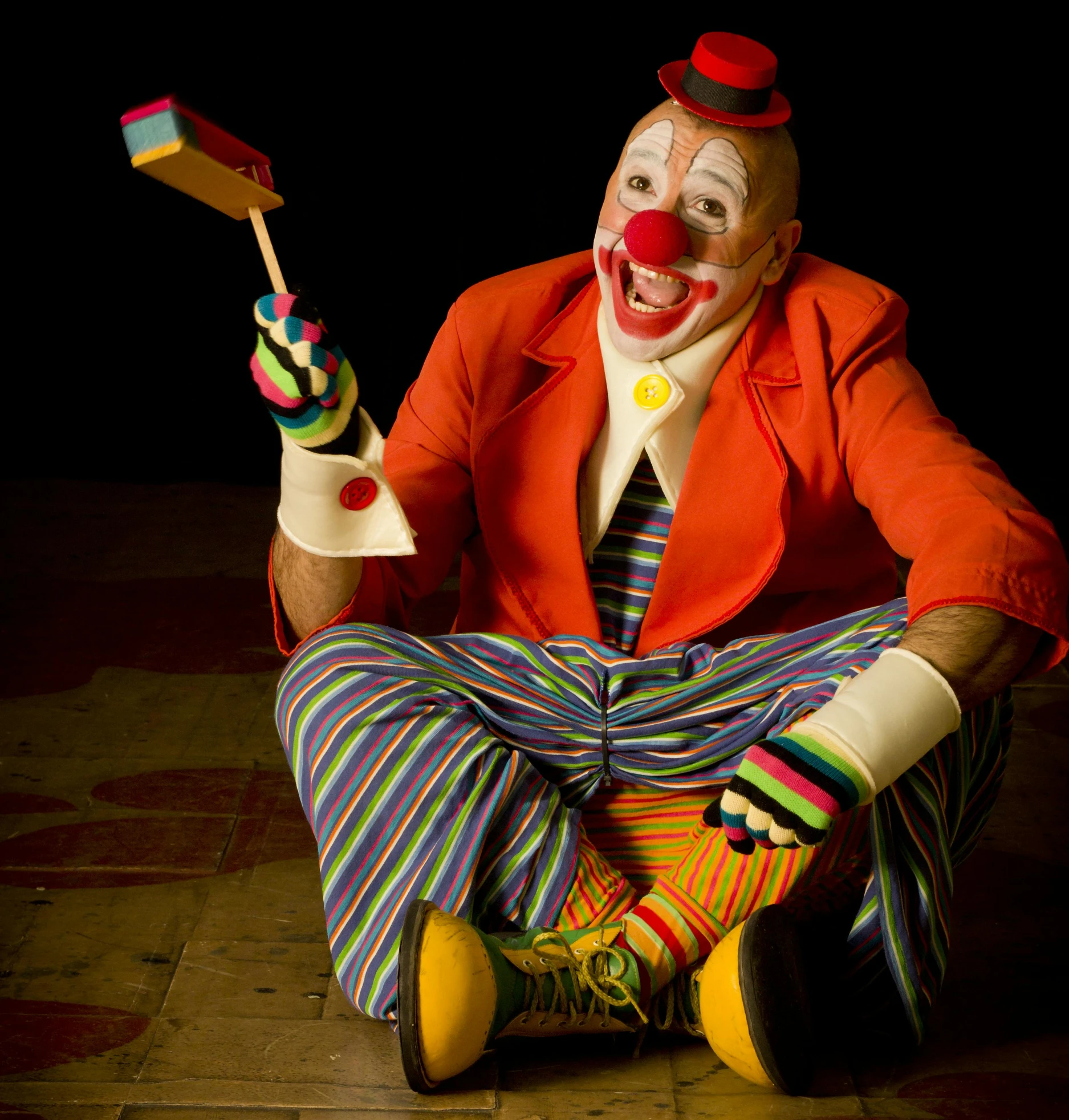 a clown sitting down with some toy animals