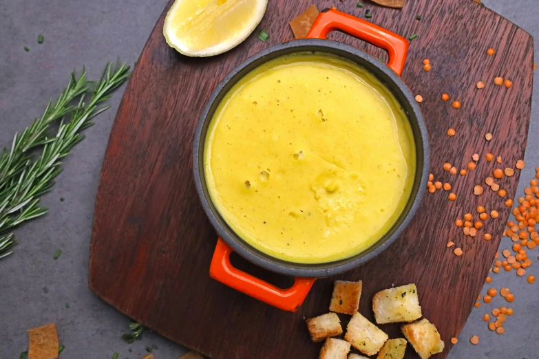 a pot of soup on top of a wooden board with ers