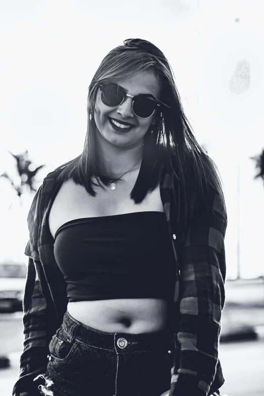 a young woman standing in a street in a crop top and jean pants