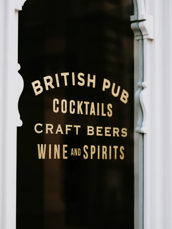 a sign on the front door of a building reads british pub cocktails, craft beers and wine spirits