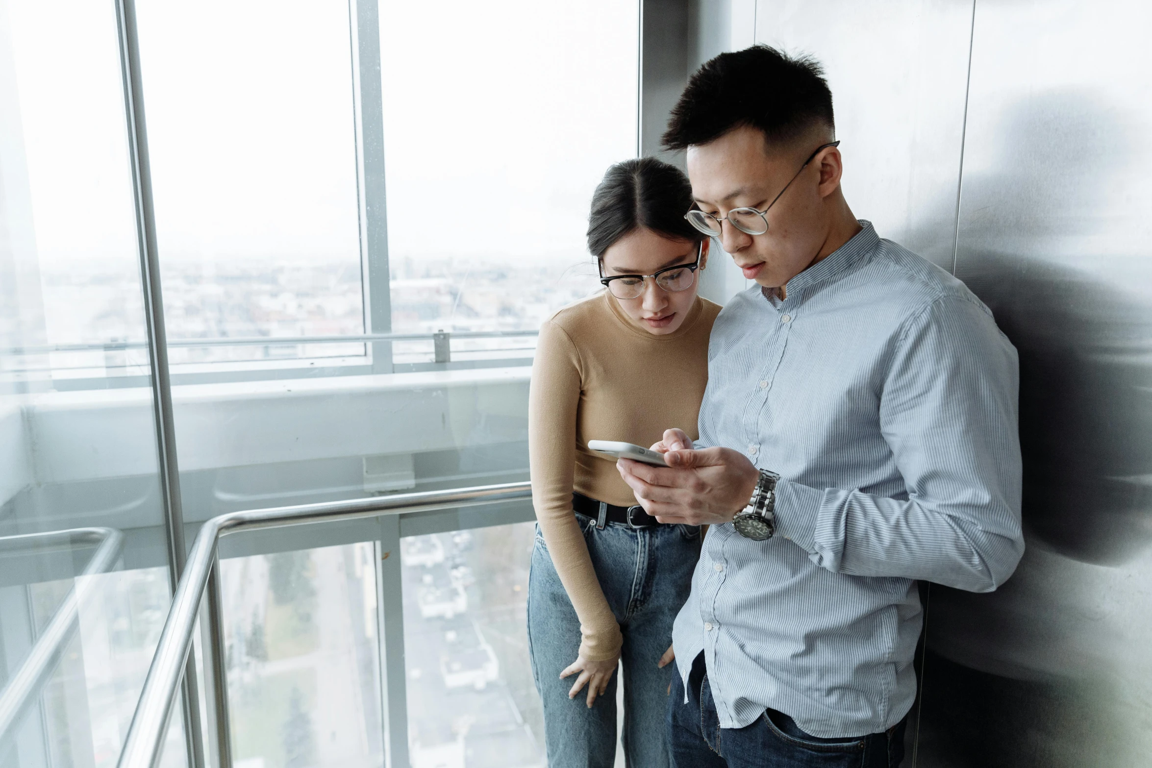 a man standing next to a woman while looking at a cell phone